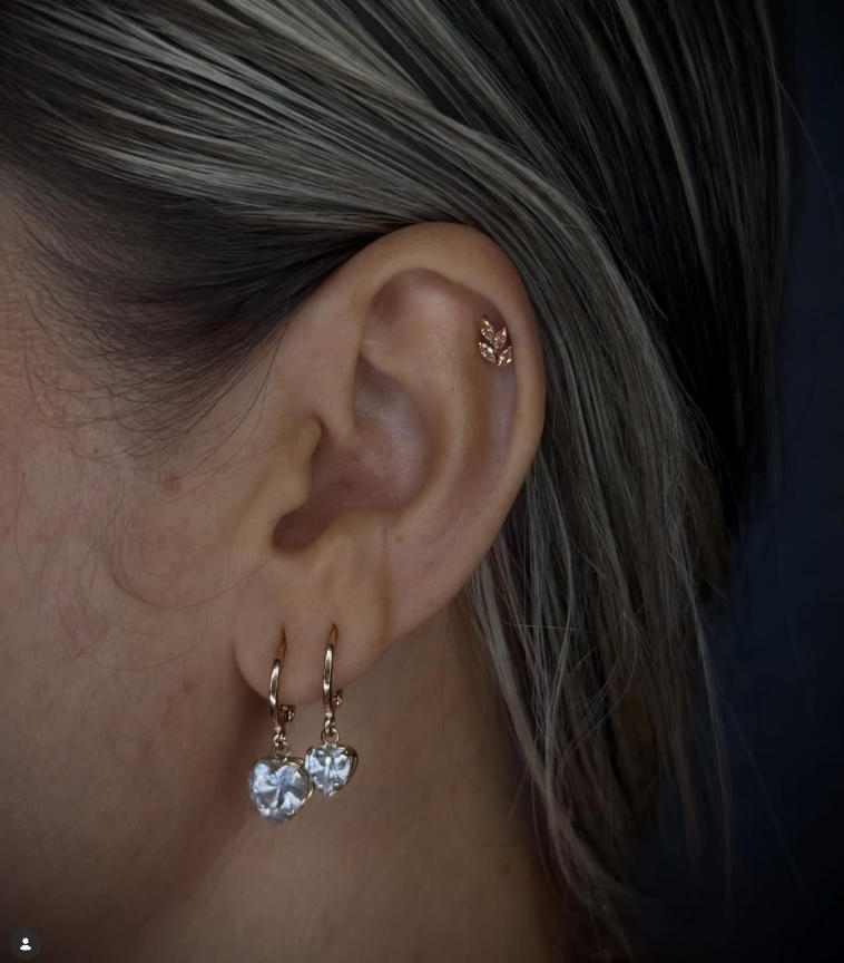 Piercing auricular com joia dourada